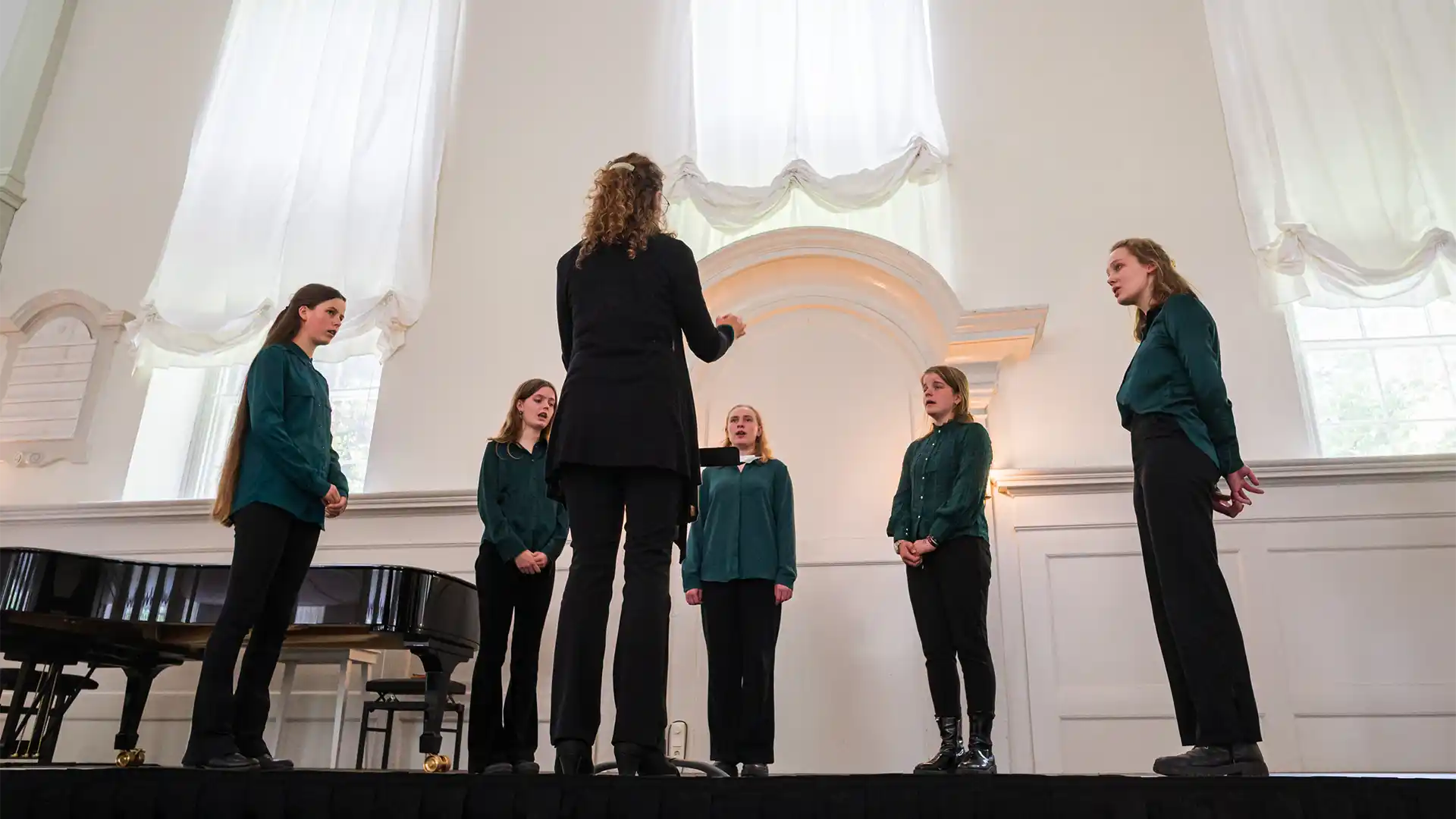 Een vrouwenkoor met dirigente.